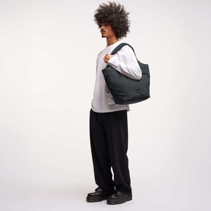 CLOUD TOTE BAG Tasche von einem Mann über der Schulter getragen.
