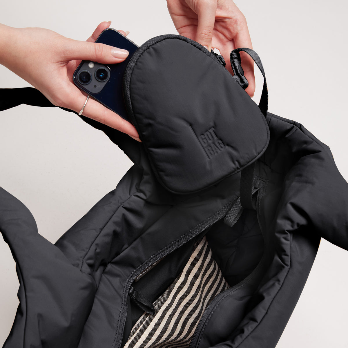 Eine Frau steckt ihr Handy in eine CLOUD TOTE BAG Tasche.