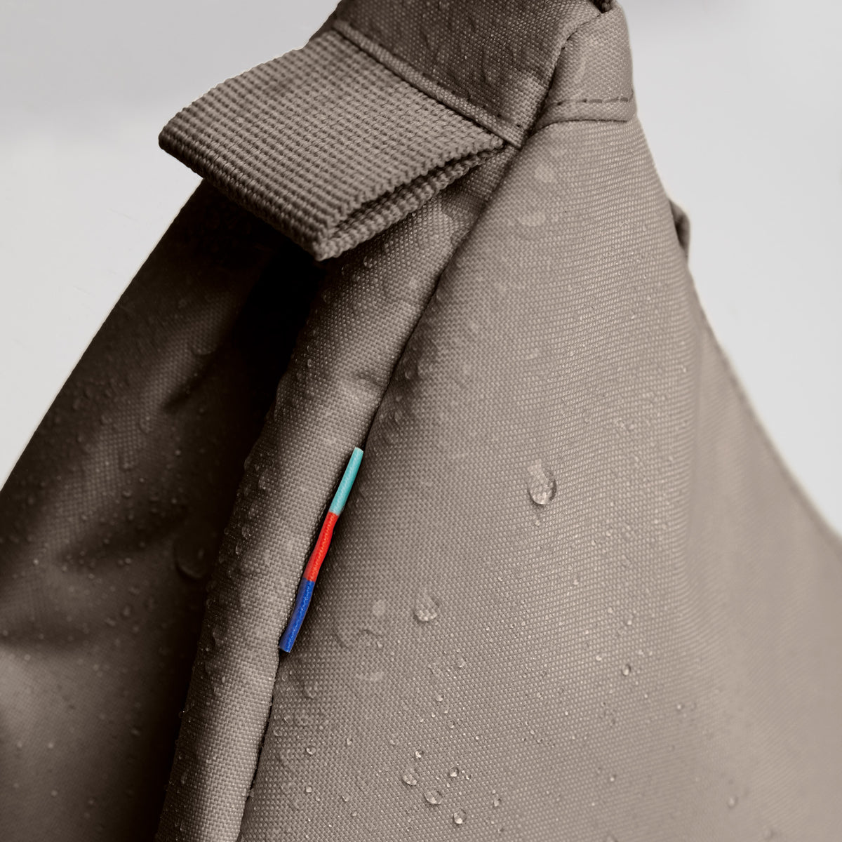 MOON BAG SMALL Tasche in seal (dunkler Beigeton) mit Wassertropfen als Detailaufnahme.