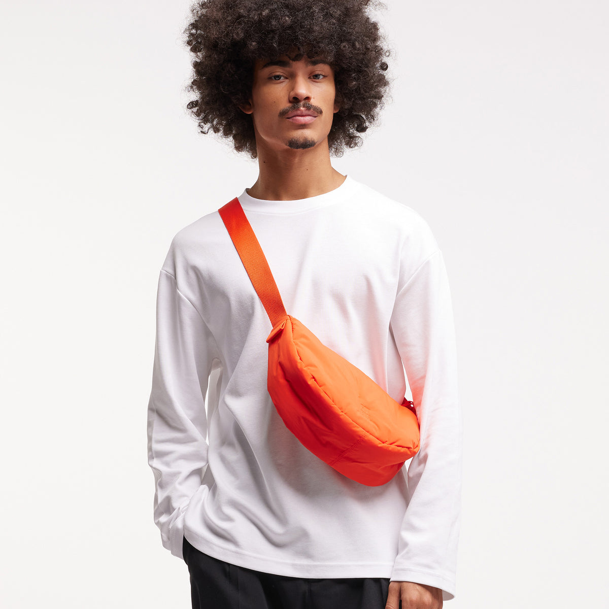 CLOUD MOON BAG SMALL Tasche in hot coral (knalliges Orange) von einem Mann crossbody getragen.