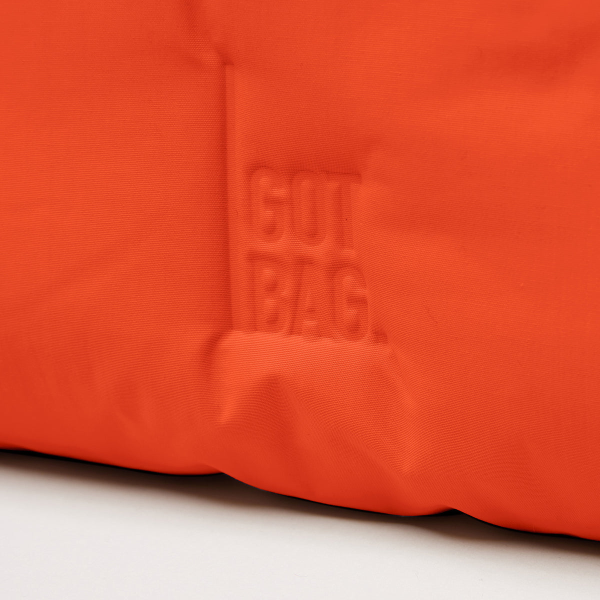 CLOUD SHOULDER Tasche in hot coral (knalliges Orange) mit eingeprägtem GUT BAG Logo.