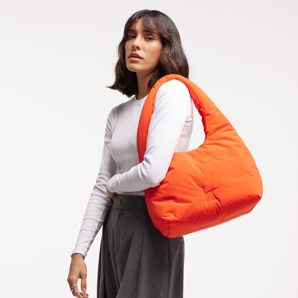 CLOUD SHOULDER Tasche in hot coral (knalliges Orange) von einer Frau über der Schulter getragen.