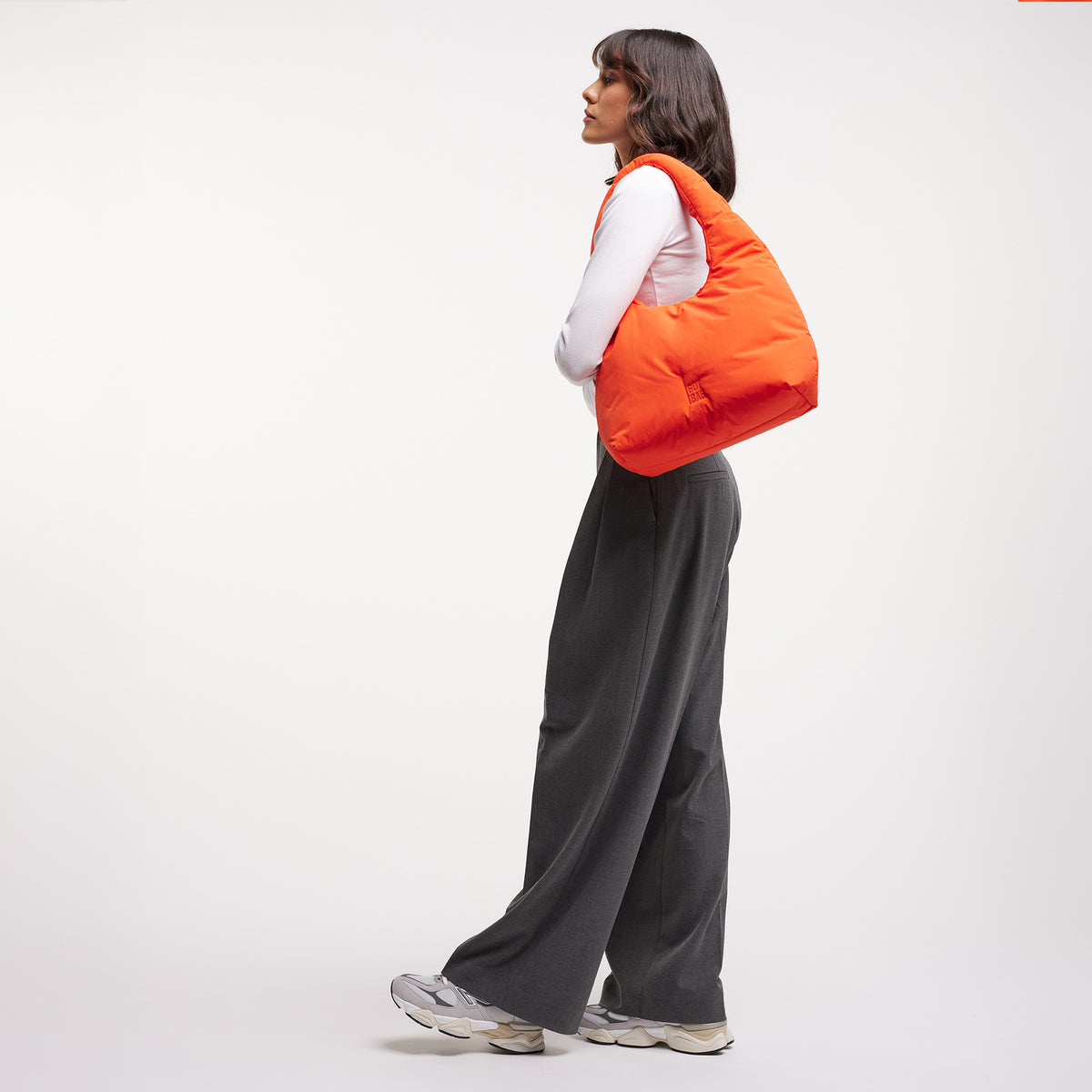 CLOUD SHOULDER Tasche in hot coral (knalliges Orange) von einer Frau über der Schulter getragen.