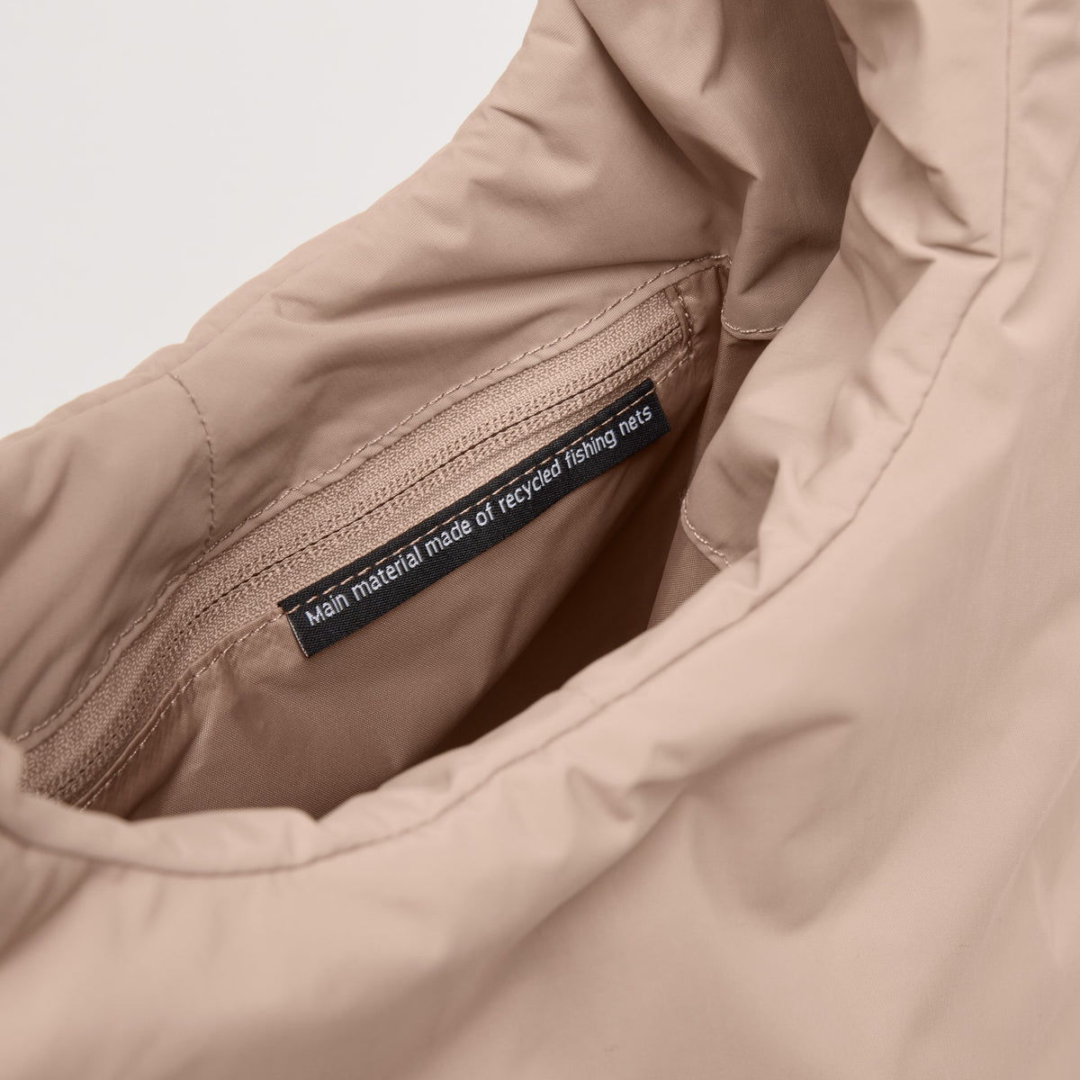 CLOUD SHOULDER Tasche in sandbar (warmes Beige mit rötlichem Unterton), innen mit Reißverschluss und Etikett.