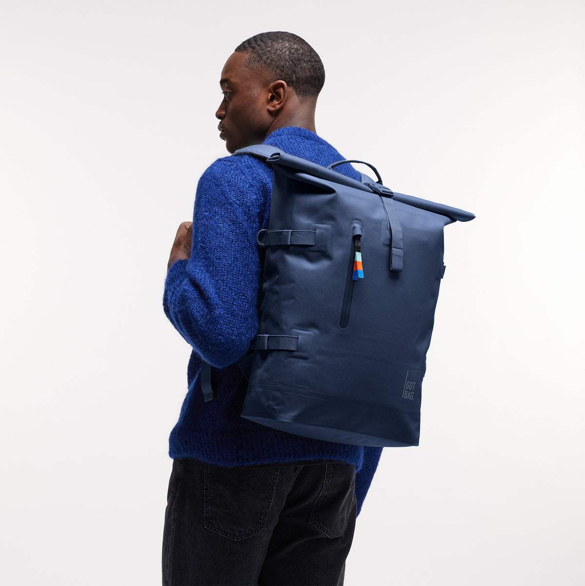 ROLLTOP Rucksack in deep ocean (dunkles Marineblau) von einem Mann als Rucksack auf dem Rücken getragen.