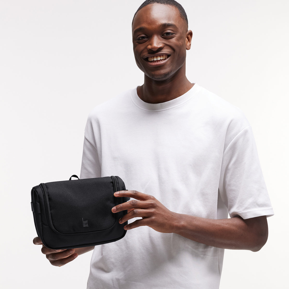 SHOWER KIT Tasche in black (Schwarz) von einem Mann in der Hand gehalten.