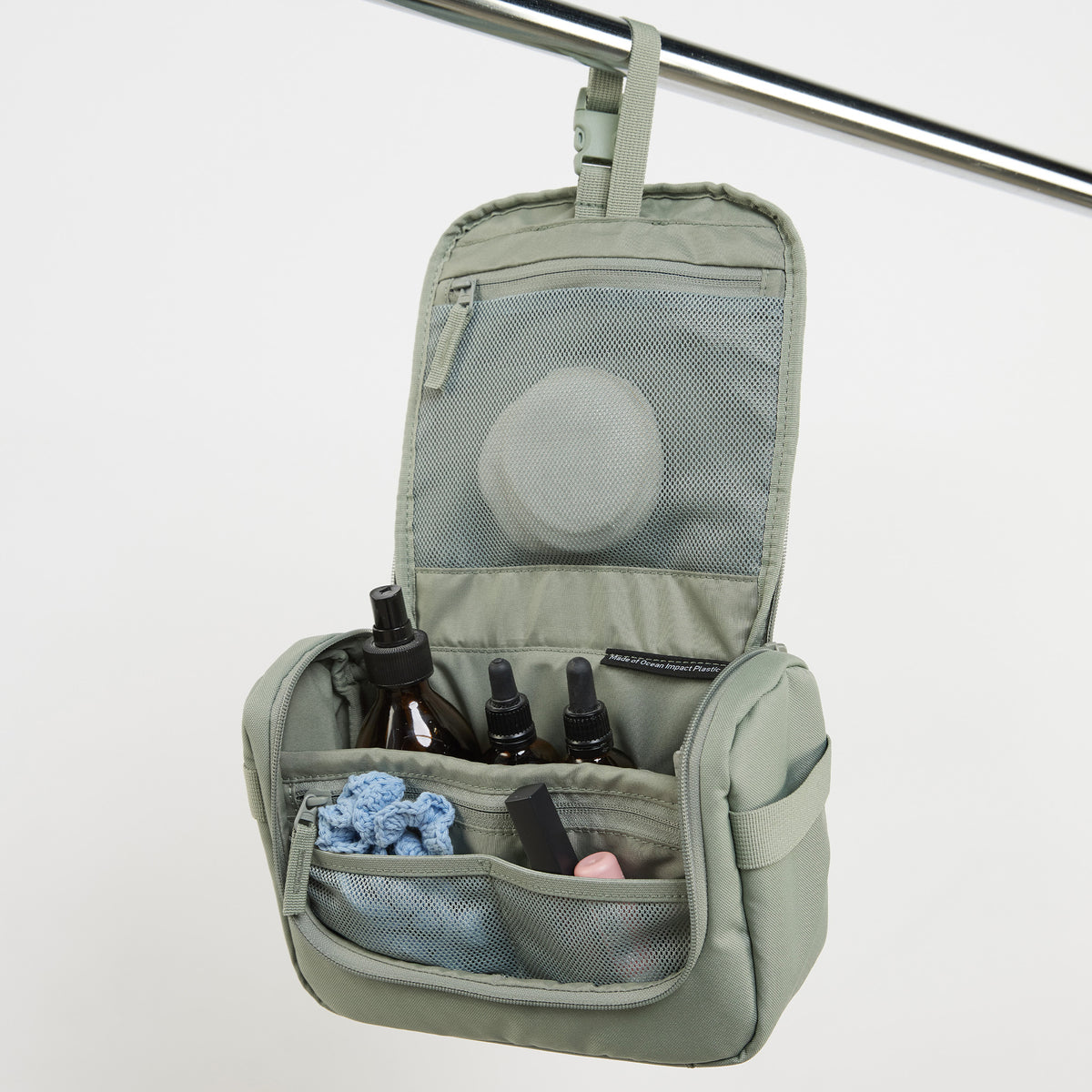 SHOWER KIT Accessoires in bass (Salbeigrün), offen hängend mit Flaschen und Kosmetik.