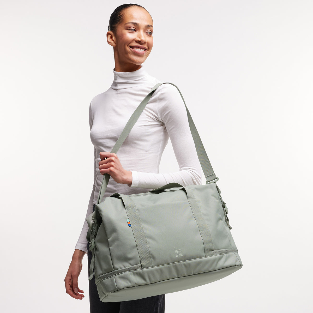 WEEKEND BAG Tasche in bass (Salbeigrün) von einer Frau über der Schulter getragen.