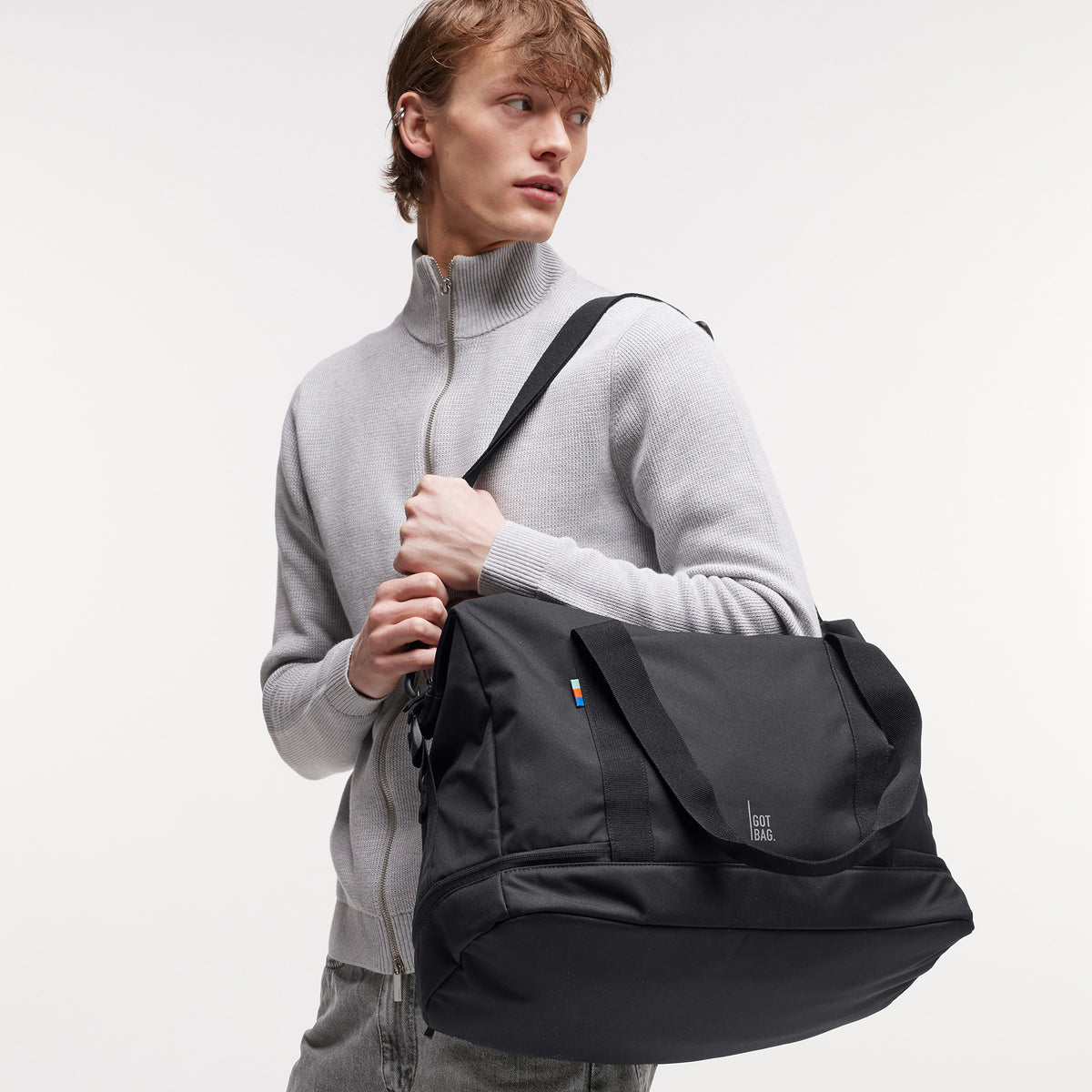 WEEKEND BAG Tasche in black (Schwarz) von einem Mann über der Schulter getragen.