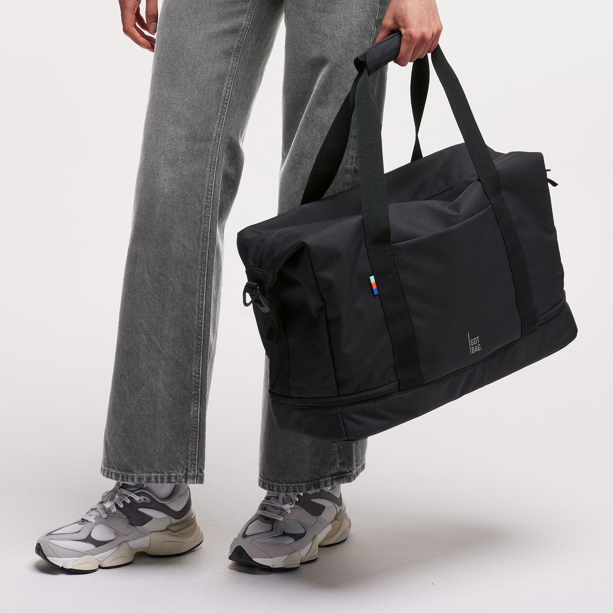WEEKEND BAG Tasche in black (Schwarz) von einer Frau in der Hand gehalten.