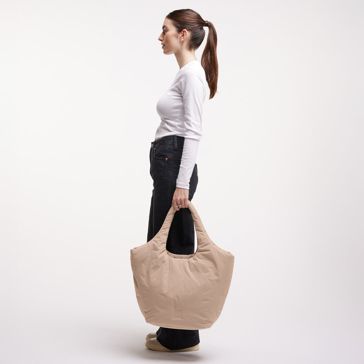 CLOUD TOTE BAG Tasche in sandbar (warmes Beige mit rötlichem Unterton) von einer Frau in der Hand gehalten.
