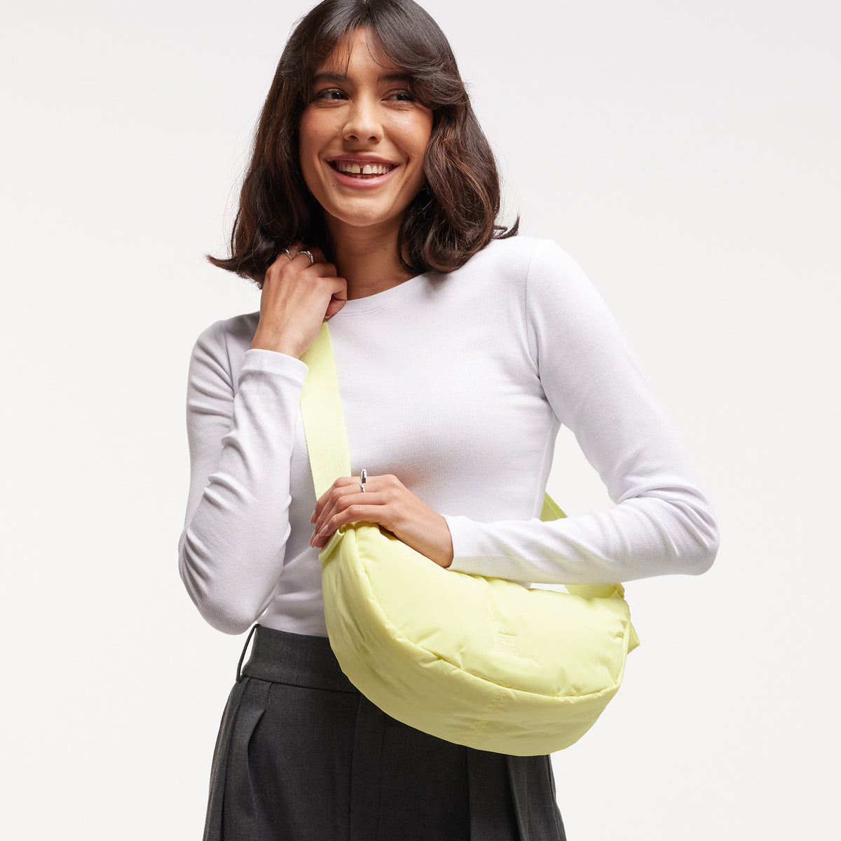CLOUD MOON BAG SMALL Tasche in sea lemon (zartes Pastellgelb) von einer Frau über der Schulter getragen.