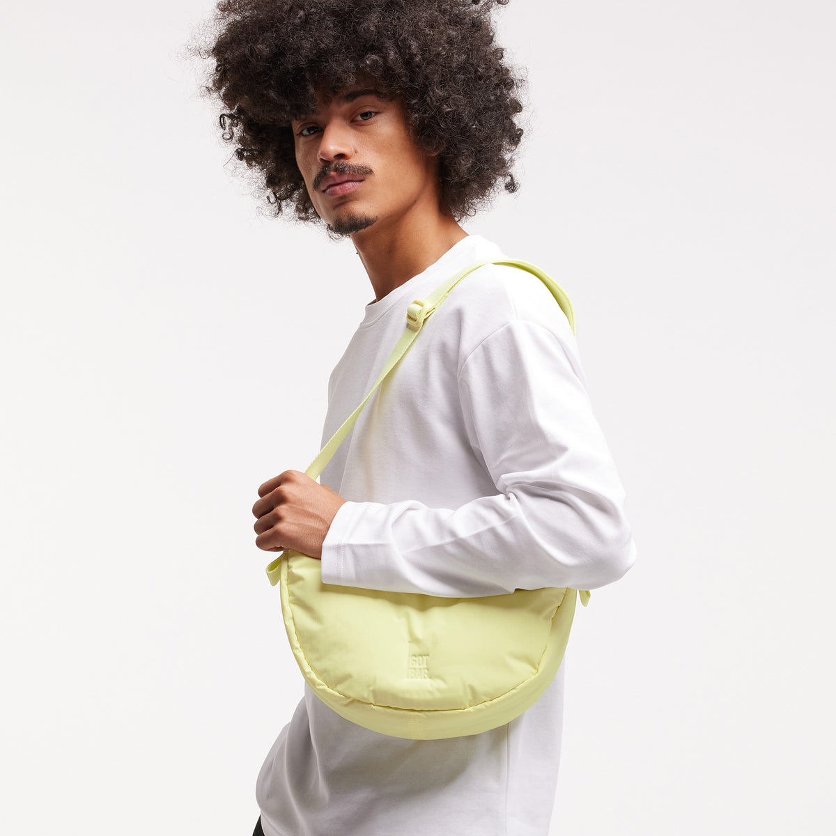 CLOUD MOON BAG SMALL Tasche in sea lemon (zartes Pastellgelb) von einem Mann crossbody getragen.