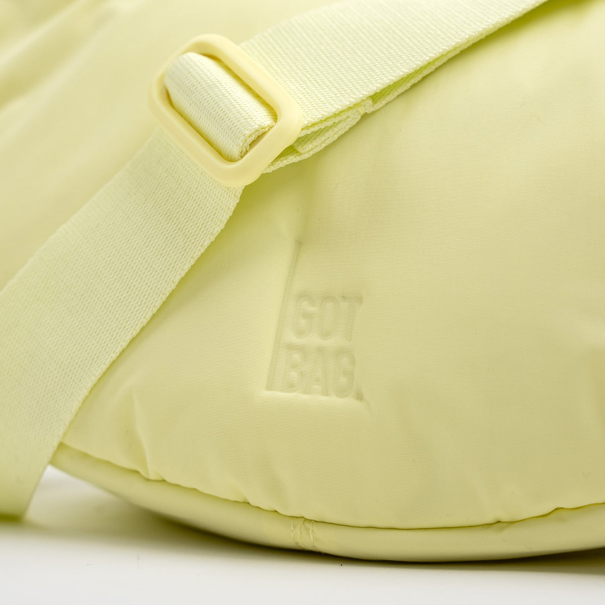 CLOUD MOON BAG SMALL Tasche in sea lemon (zartes Pastellgelb) als Detailaufnahme mit geprägtem Logo.