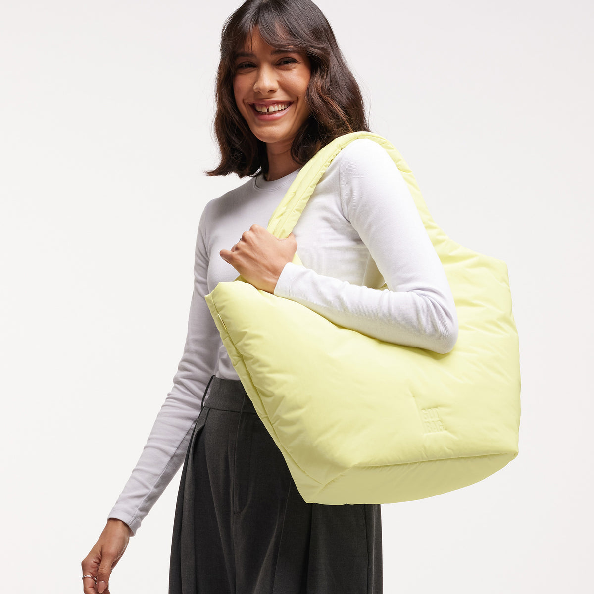 CLOUD TOTE BAG Tasche in sea lemon (zartes Pastellgelb) von einer Frau über der Schulter getragen.