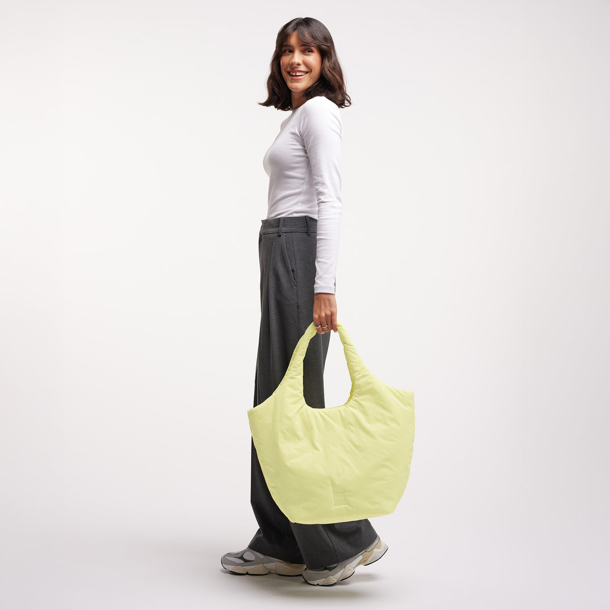 CLOUD TOTE BAG Tasche in sea lemon (zartes Pastellgelb) von einer Frau in der Hand gehalten.