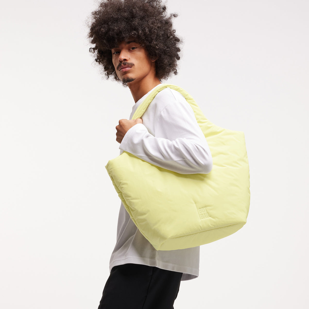 CLOUD TOTE BAG Tasche in sea lemon (zartes Pastellgelb) von einem Mann über der Schulter getragen.