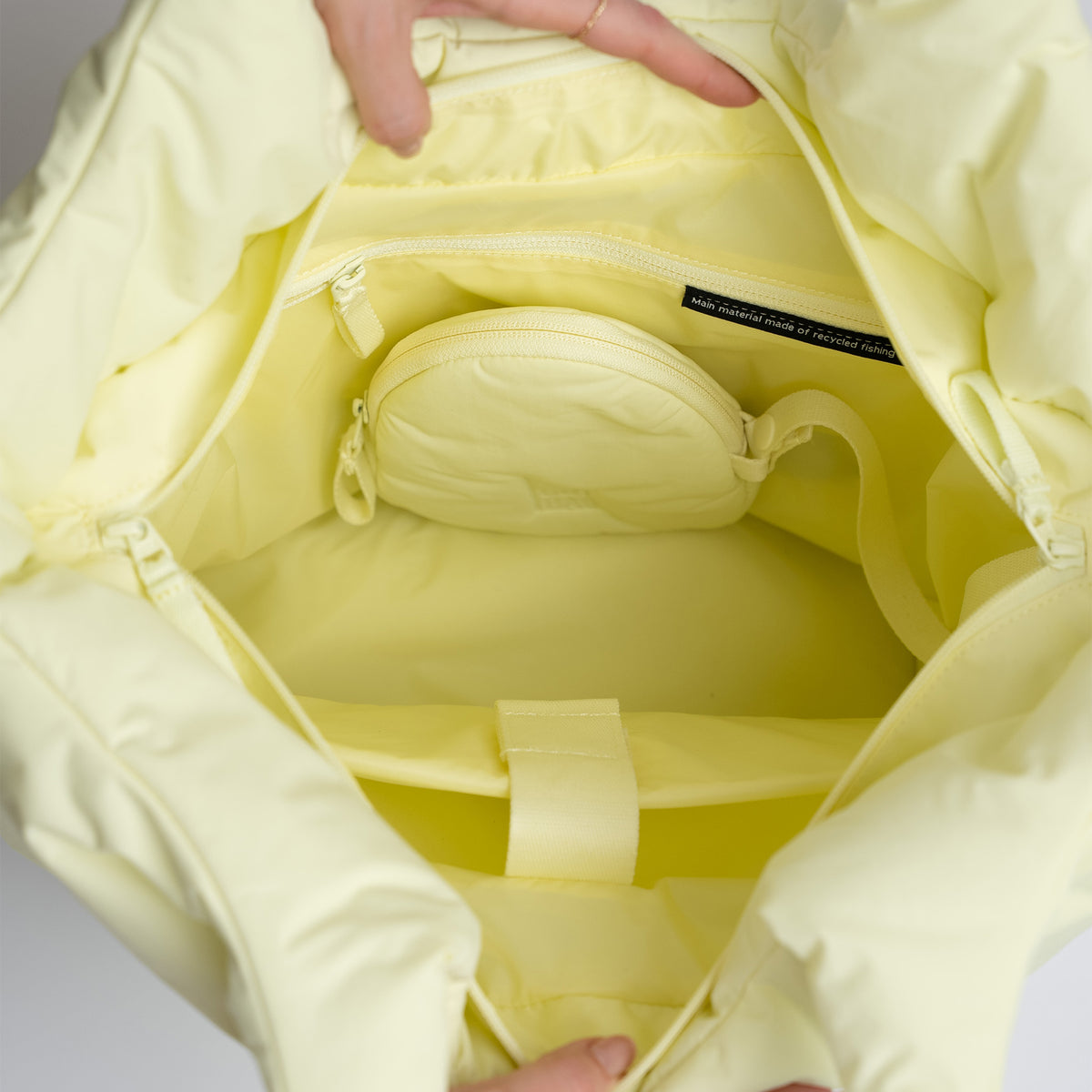 CLOUD TOTE BAG Tasche in sea lemon (zartes Pastellgelb), von Händen geöffnet, zeigt den Innenraum.