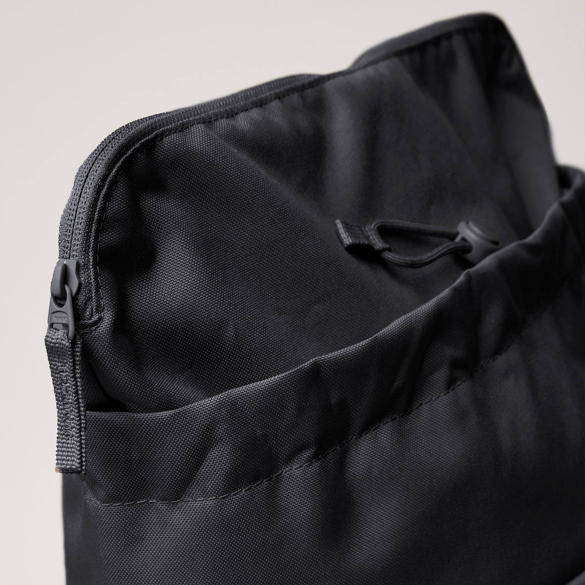 BARREL PACK Tasche in black (Schwarz) als Detailaufnahme mit Reißverschluss und Kordelzug oben.