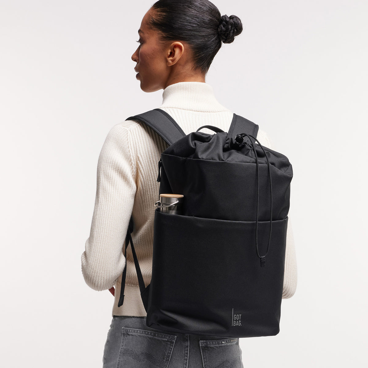 BARREL PACK Rucksack in black (Schwarz) von einer Frau als Rucksack auf dem Rücken getragen.