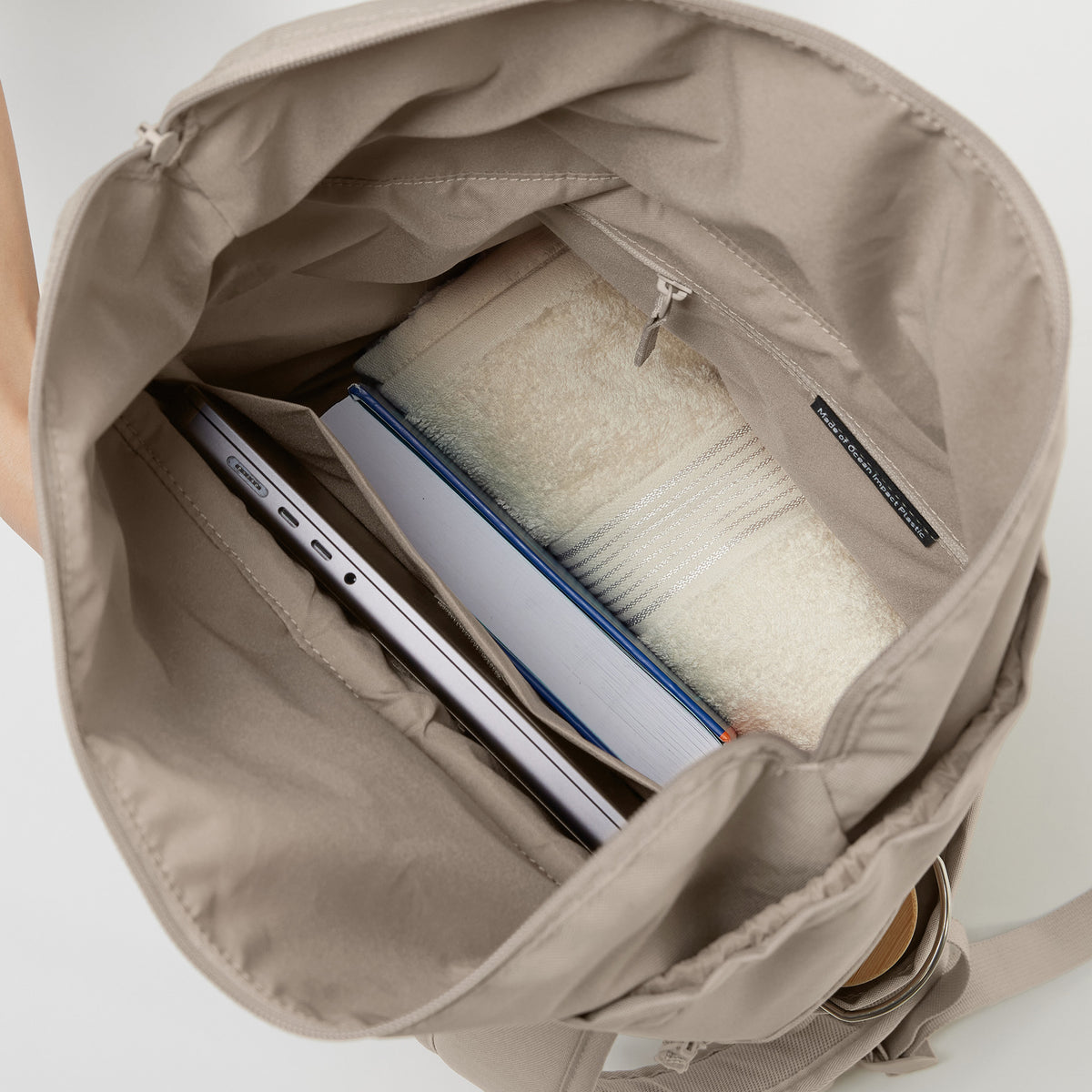 BARREL PACK Rucksack in scallop (helles Beige) mit Laptop, Buch und Handtuch im Inneren.