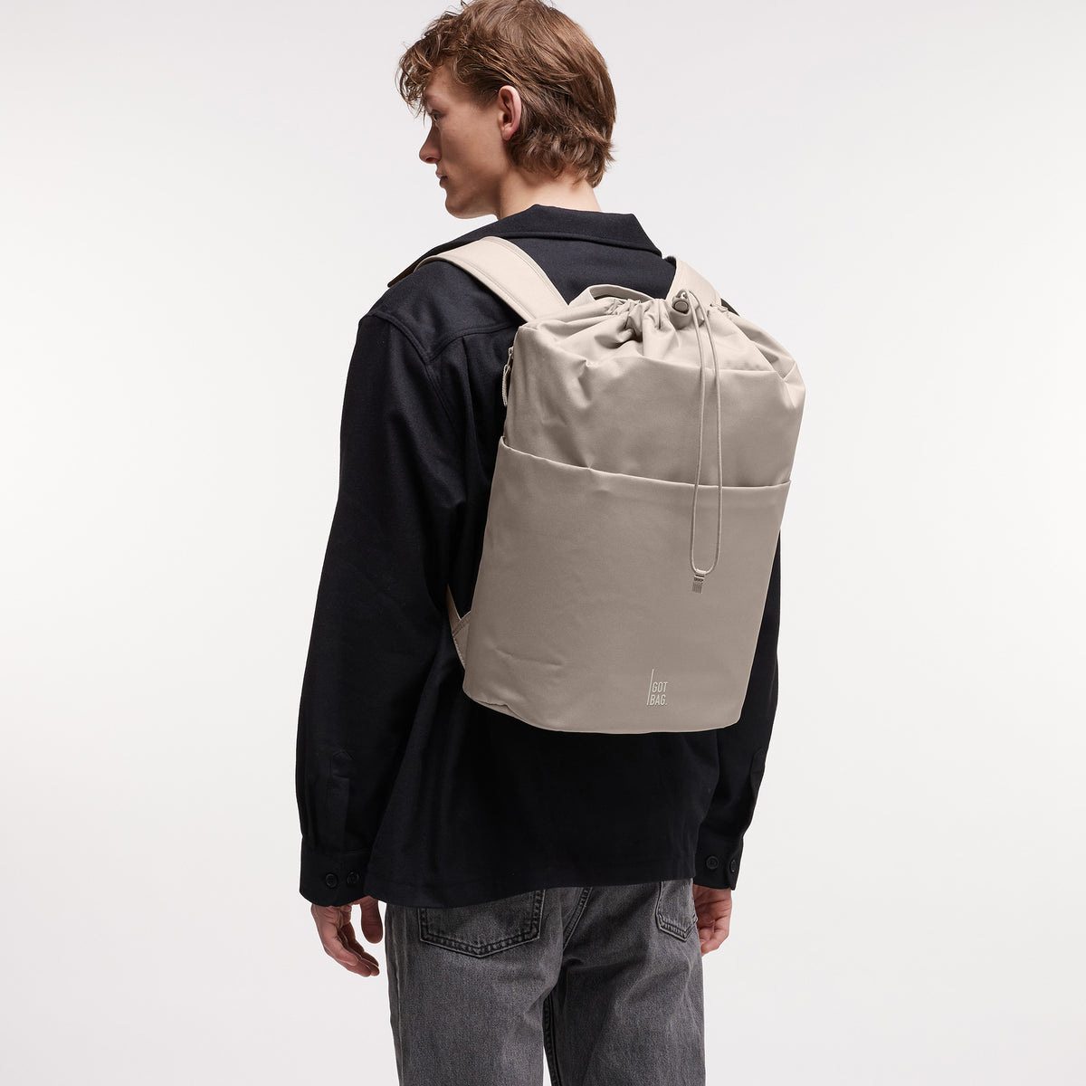 BARREL PACK Rucksack in scallop (helles Beige) von einem Mann als Rucksack auf dem Rücken getragen.