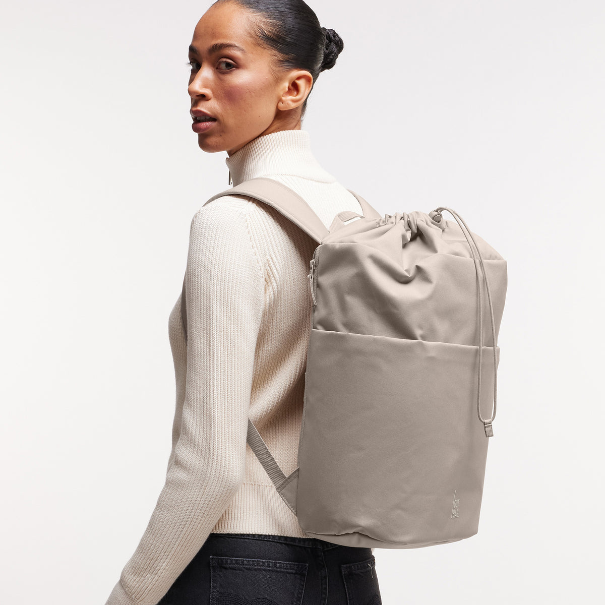 BARREL PACK Rucksack in scallop (helles Beige) von einer Frau auf dem Rücken getragen.