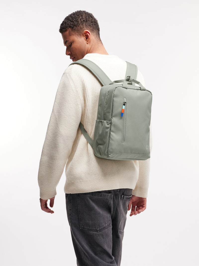 DAYPACK 2.0 Rucksack in bass (Salbeigrün) von einem Mann als Rucksack auf dem Rücken getragen.