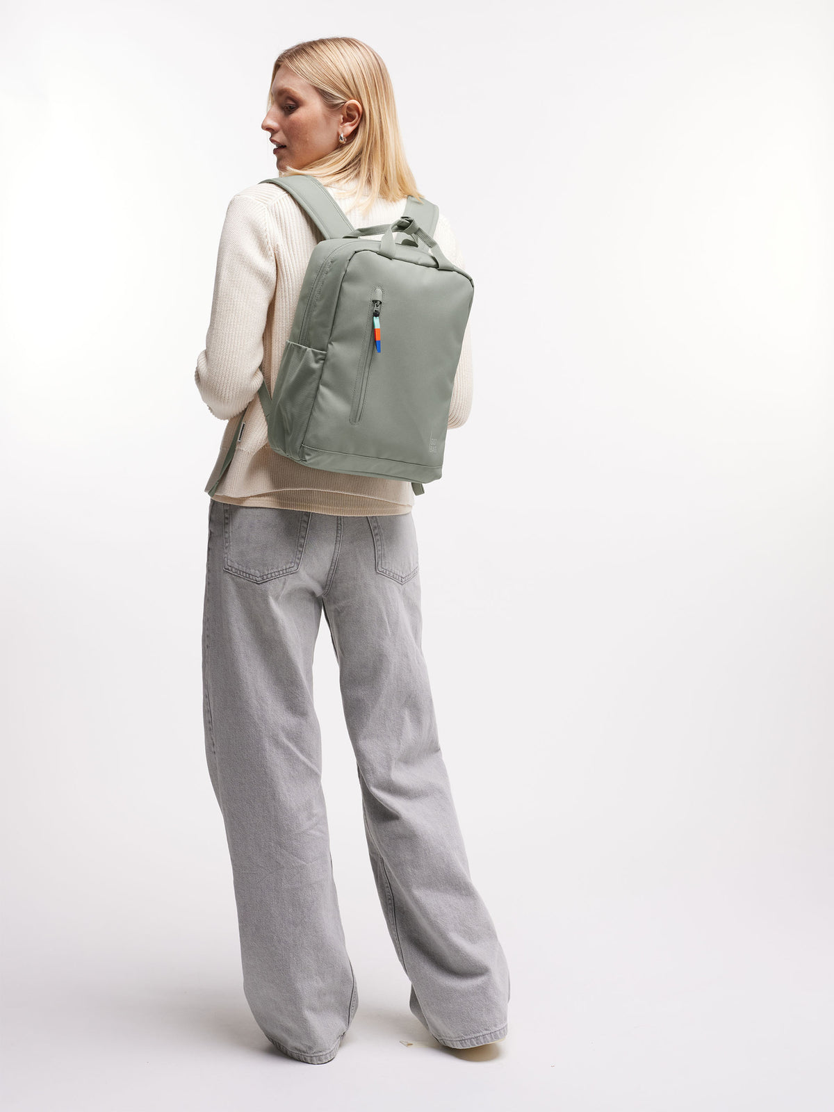 DAYPACK Rucksack in bass (Salbeigrün) von einer Frau auf dem Rücken getragen.