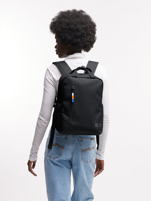 DAYPACK Rucksack in black (Schwarz) von einer Frau als Rucksack auf dem Rücken getragen.