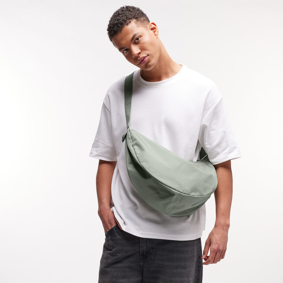 MOON BAG LARGE Monochrome Edition Tasche in bass (Salbeigrün) von einem Mann crossbody getragen.