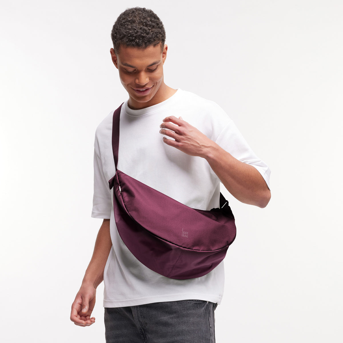 MOON BAG LARGE Tasche in kraken (Weinrot) von einem Mann crossbody getragen.