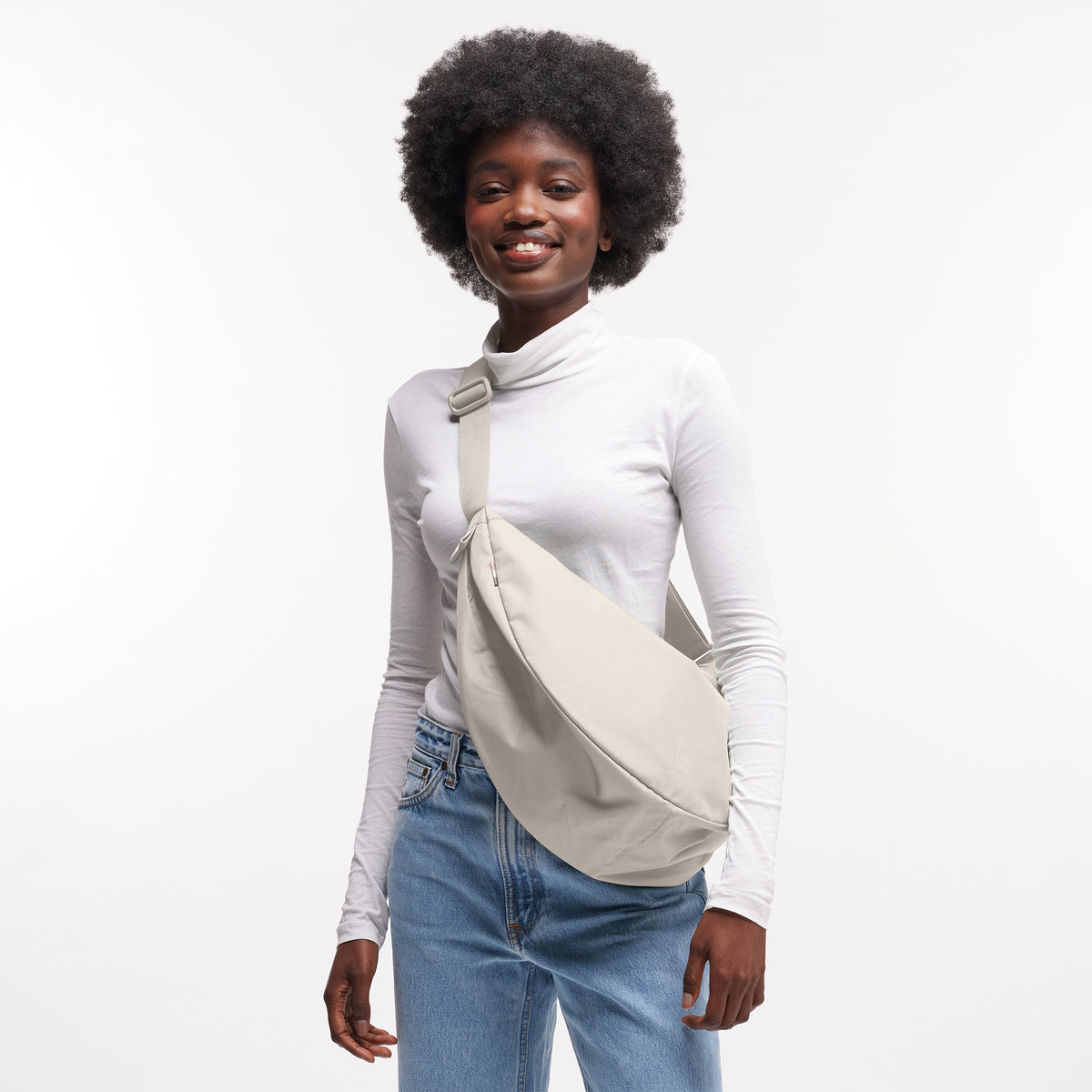 MOON BAG LARGE Tasche in soft shell (warmes Cremeweiß) von einer Frau crossbody getragen.