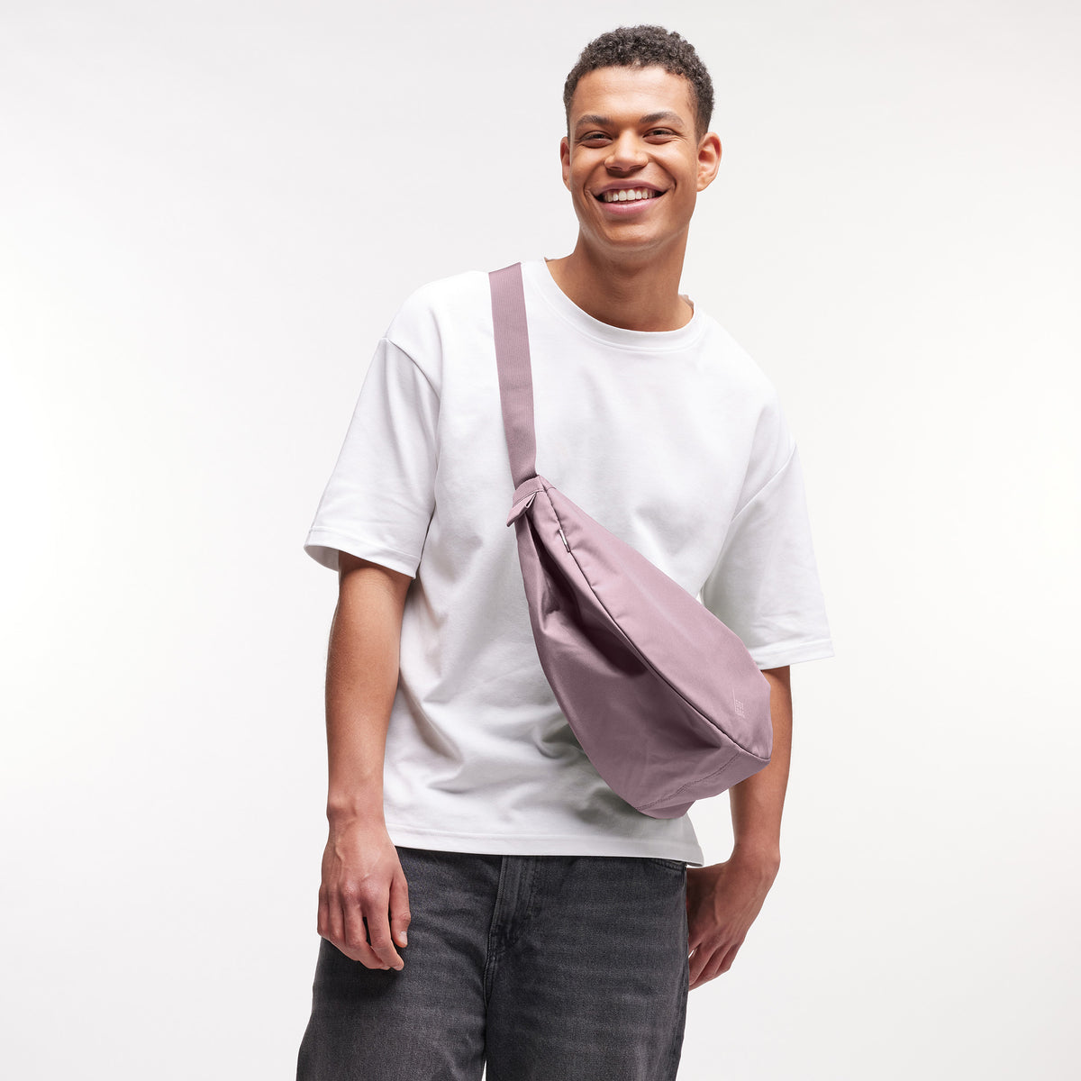MOON BAG LARGE Tasche in calamary (Altrosa) von einem Mann crossbody getragen.