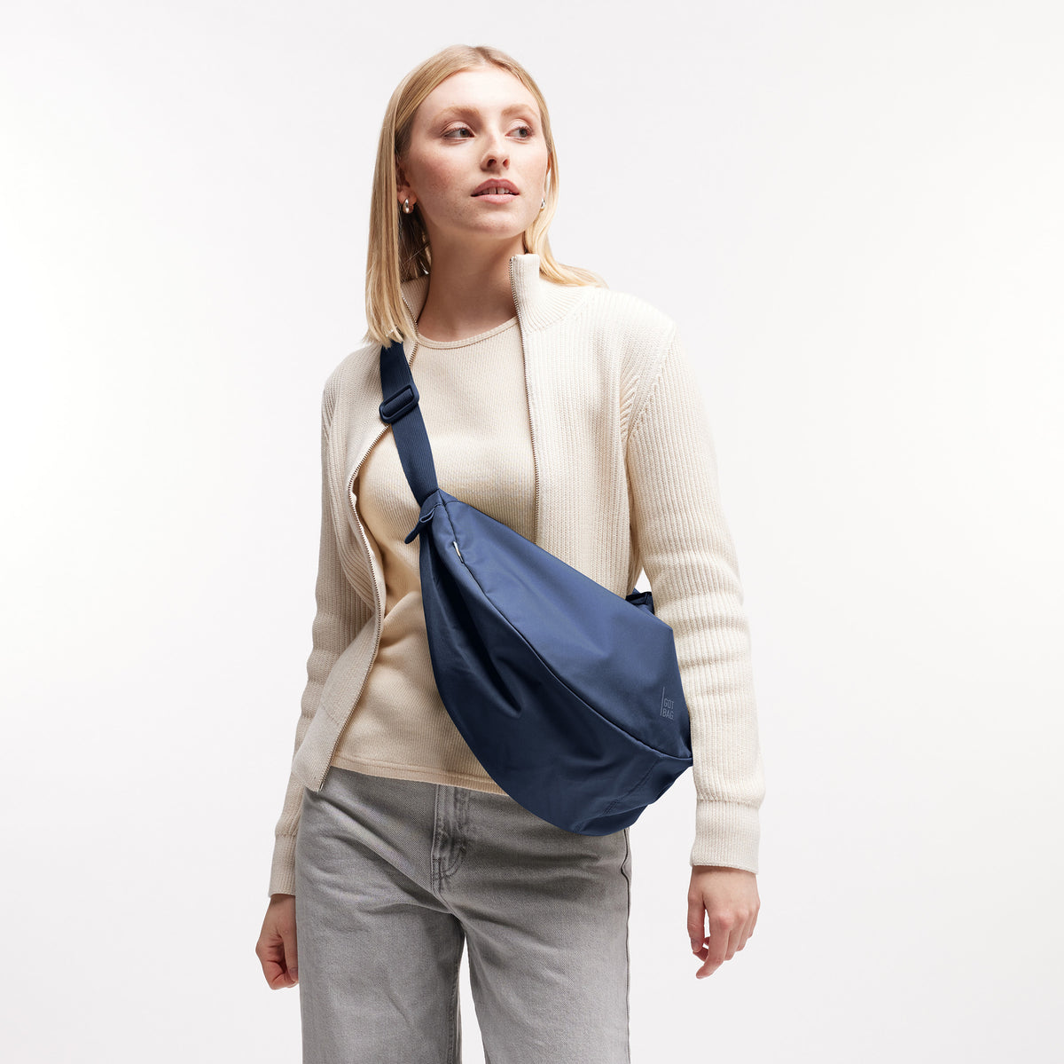 MOON BAG LARGE Tasche in deep ocean (dunkles Marineblau) von einer Frau crossbody getragen.