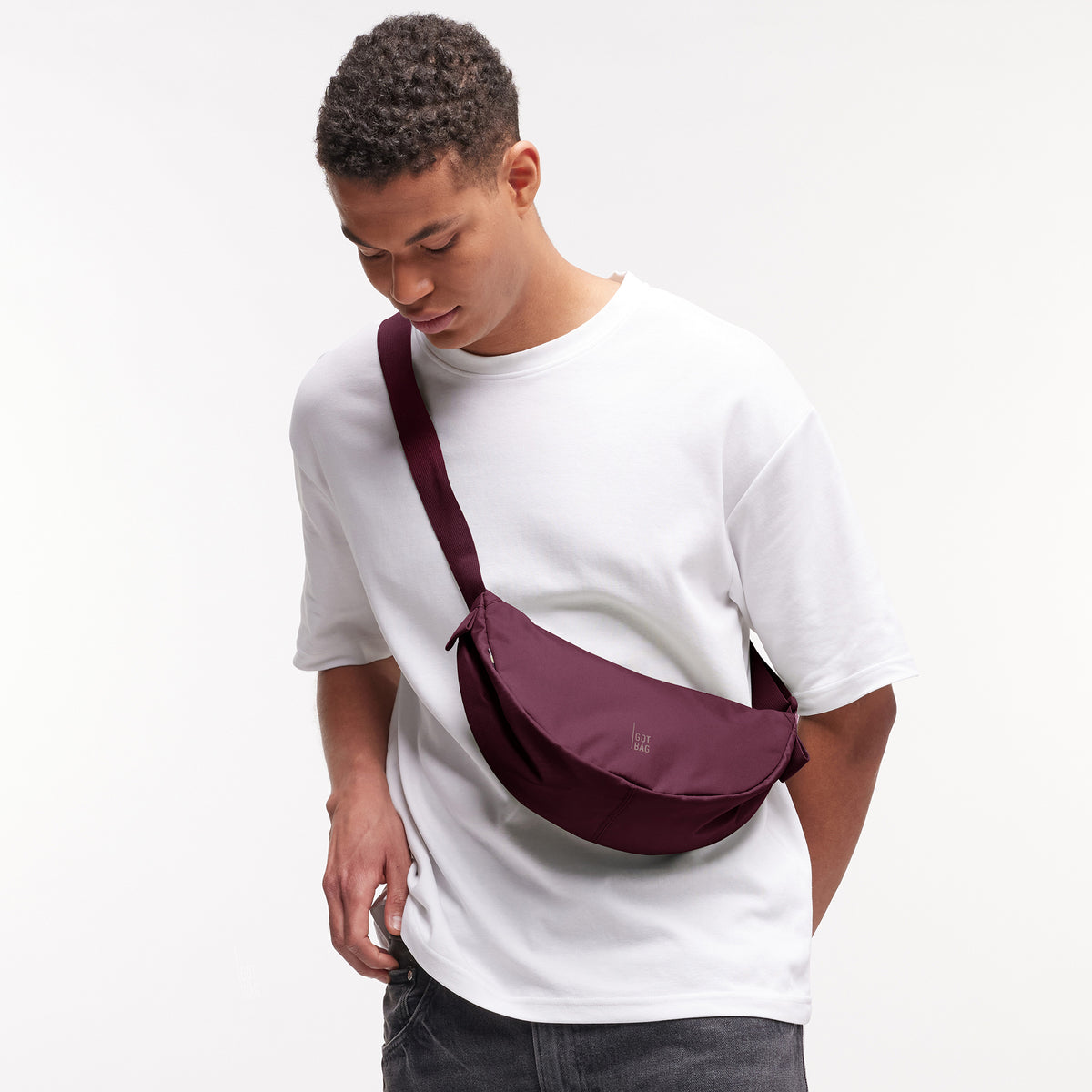 MOON BAG SMALL Tasche in kraken (Weinrot) von einem Mann crossbody getragen.