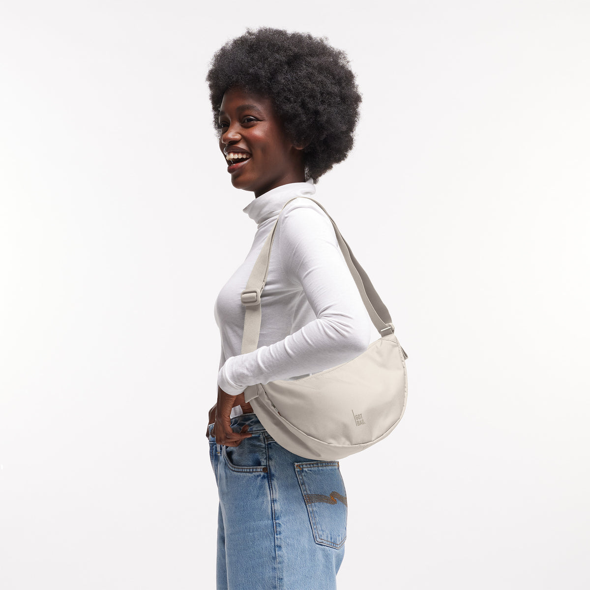 MOON BAG SMALL Tasche in soft shell (warmes Cremeweiß) von einer Frau crossbody getragen.