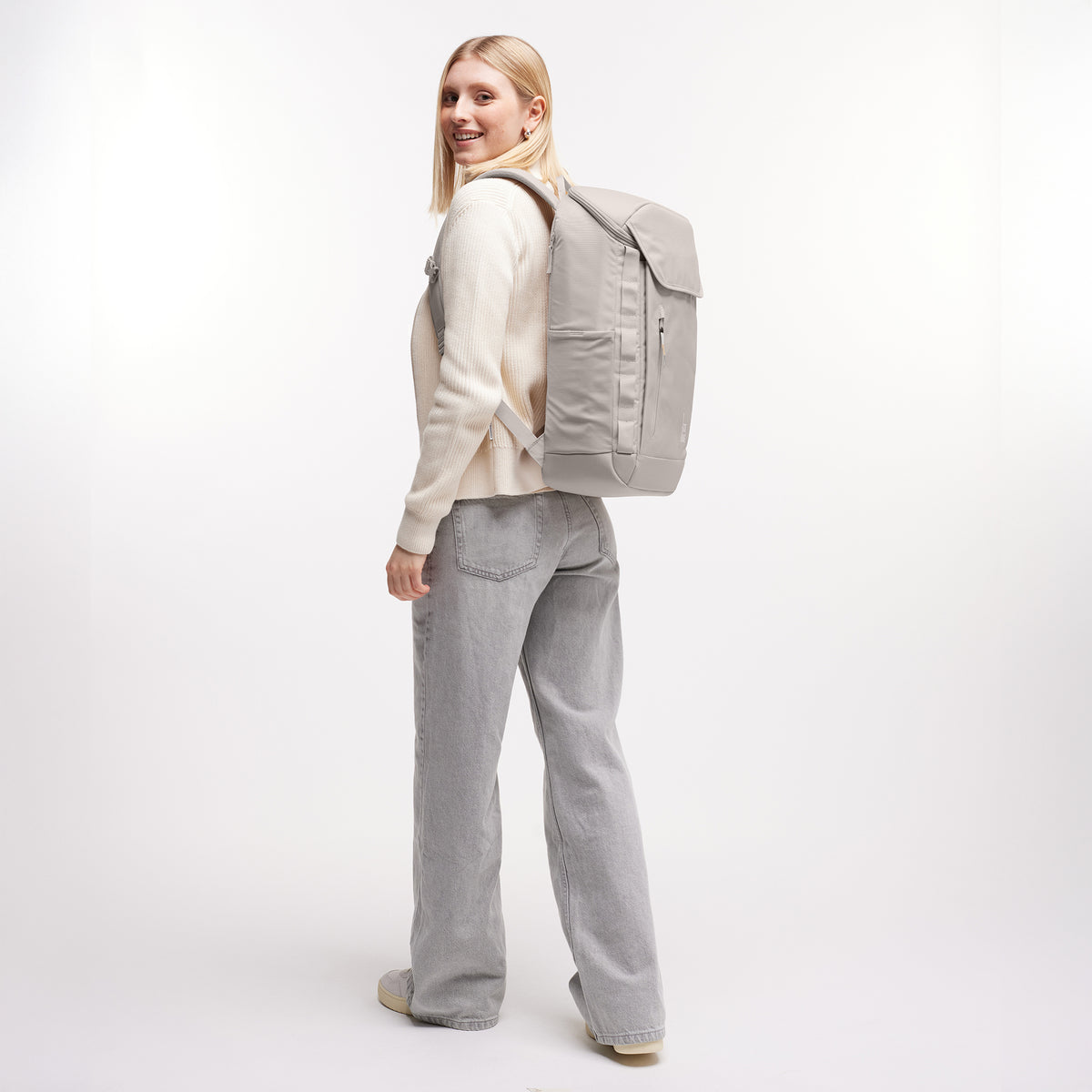 PRO PACK Rucksack in clam (helles, warmes Grau) von einer Frau als Rucksack auf dem Rücken getragen.