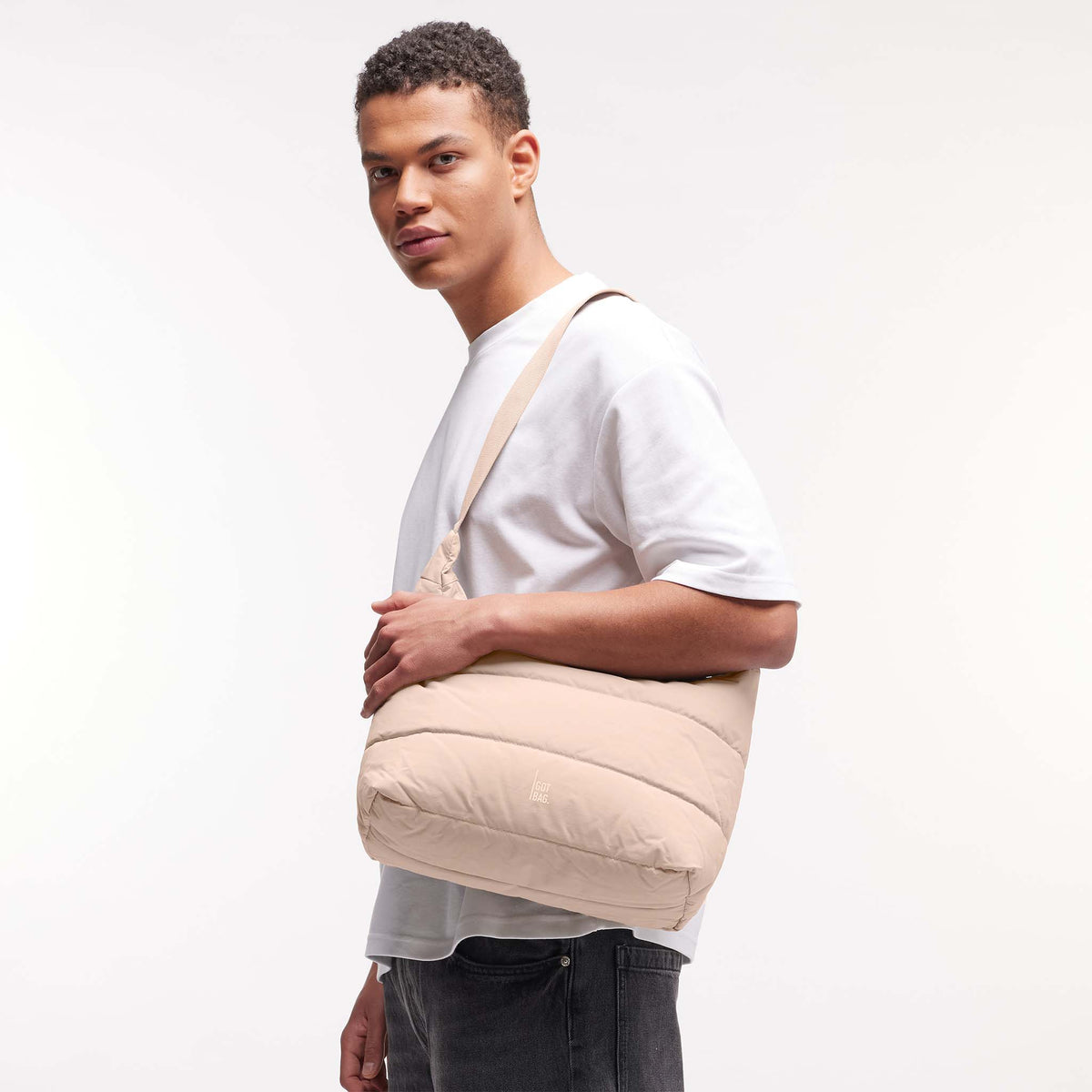 PUFFER SQUARE BAG Tasche in pearl (helles Puder-Rosa) von einem Mann crossbody getragen.