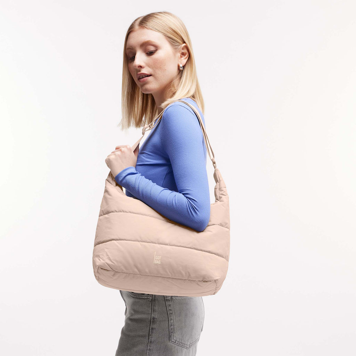 PUFFER SQUARE BAG Tasche in pearl (helles Puder-Rosa) von einer Frau über der Schulter getragen.