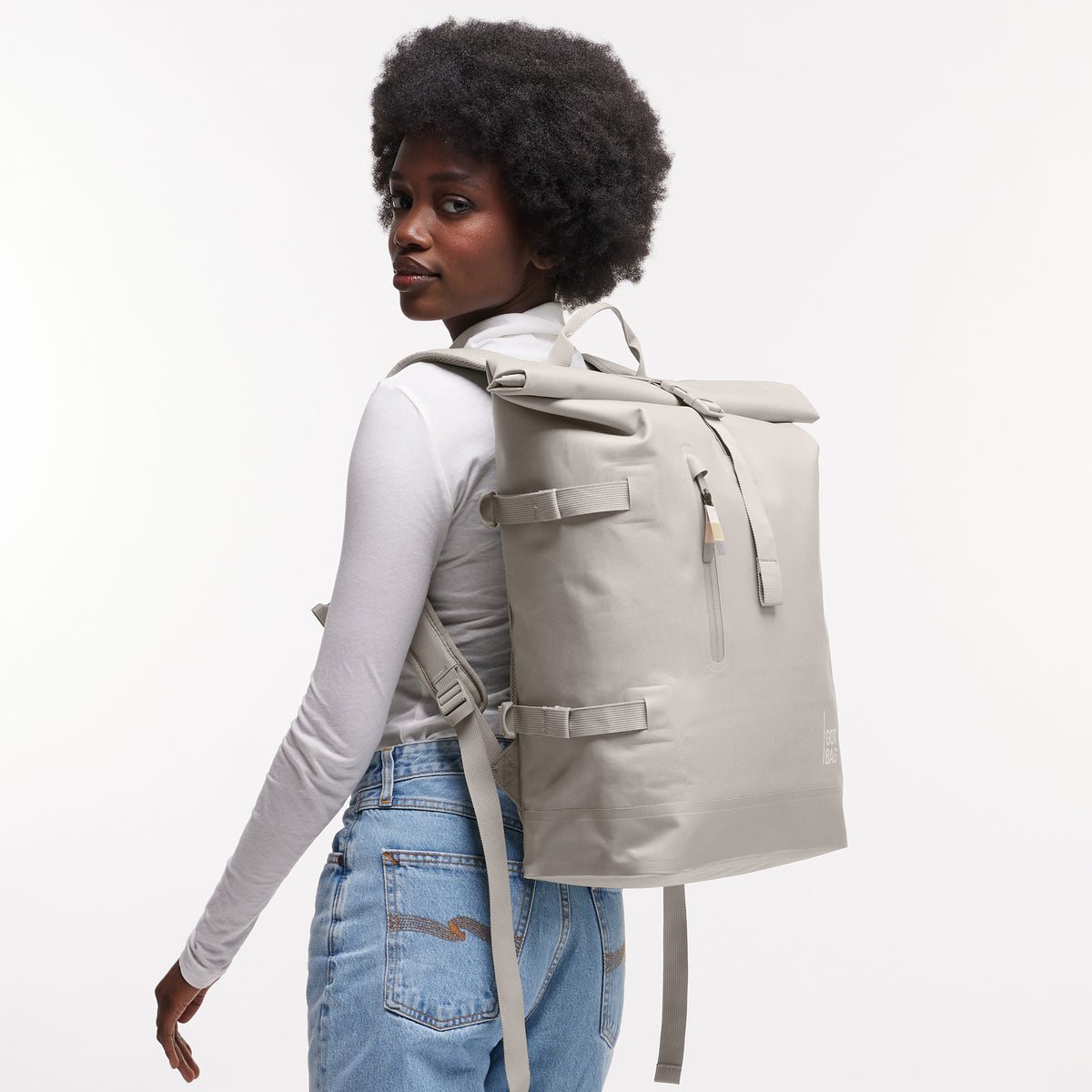ROLLTOP 2.0 MONOCHROME EDITION Rucksack in clam (helles, warmes Grau) von einer Frau als Rucksack auf dem Rücken getragen.