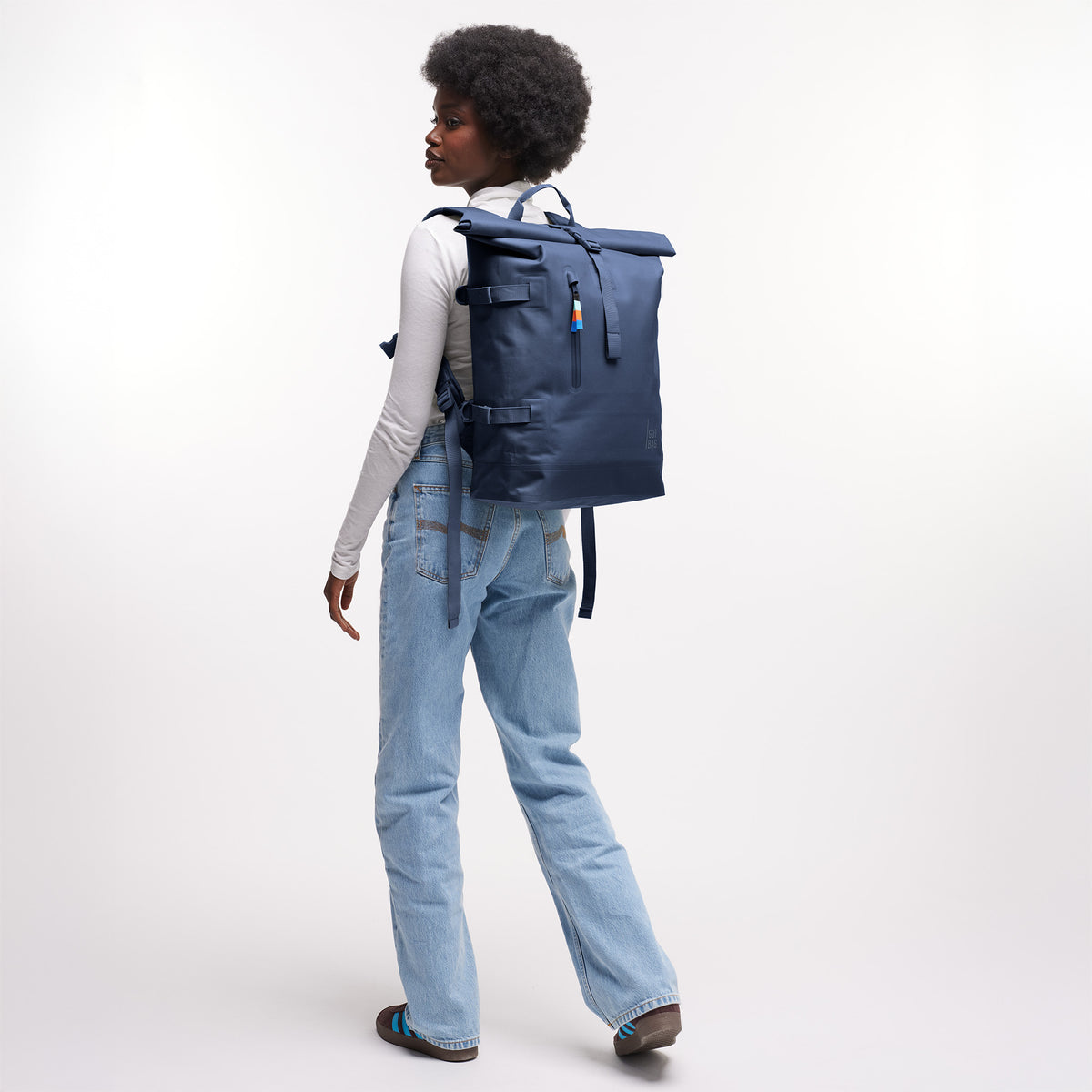 ROLLTOP 2.0 Rucksack in deep ocean (dunkles Marineblau) von einer Frau als Rucksack auf dem Rücken getragen.