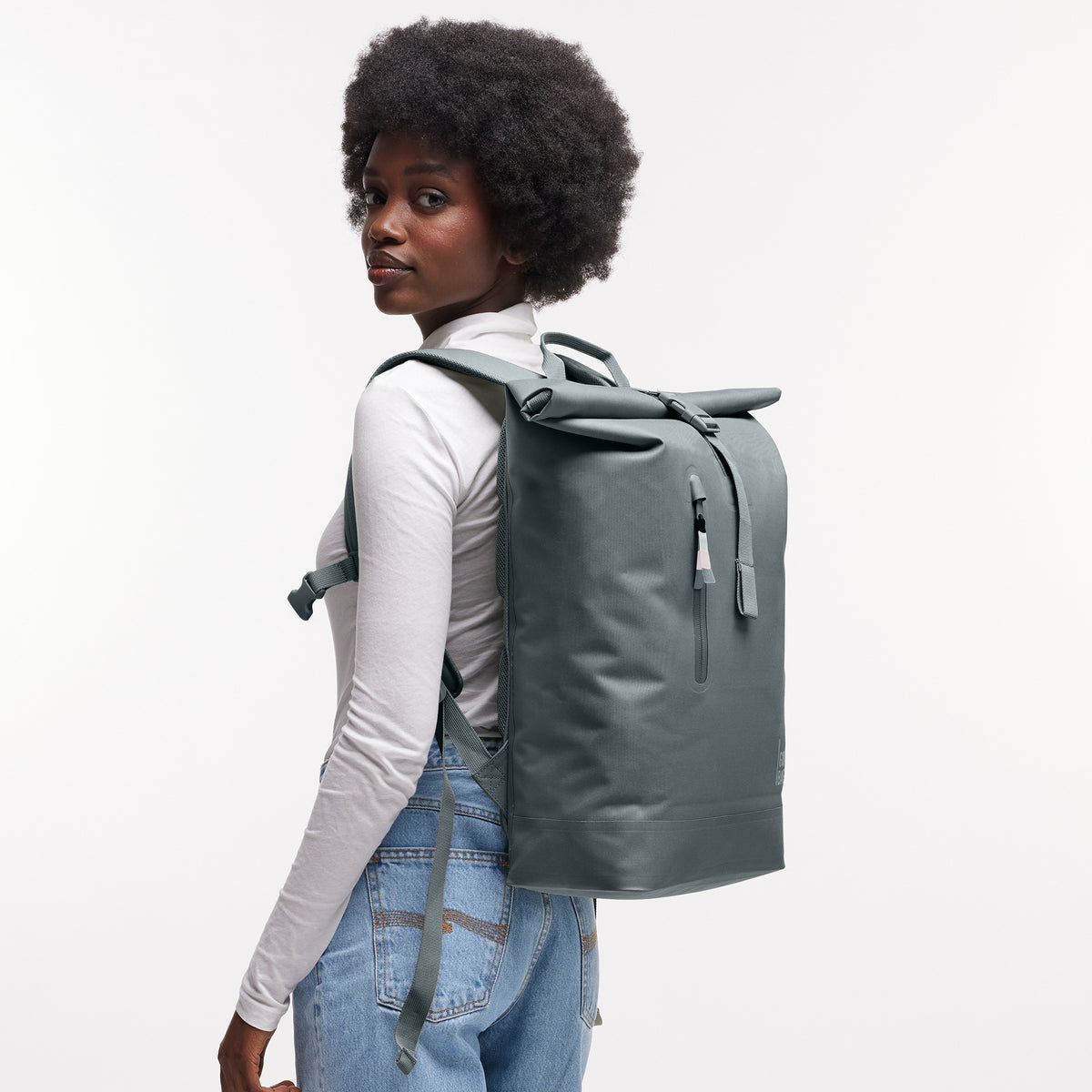 ROLLTOP LITE Rucksack in basalt (graues Eisblau) von einer Frau als Rucksack auf dem Rücken getragen.