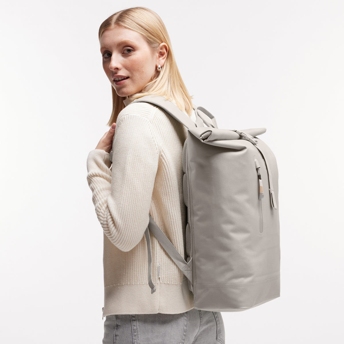 ROLLTOP LITE Rucksack in clam (helles, warmes Grau) von einer Frau auf dem Rücken getragen.