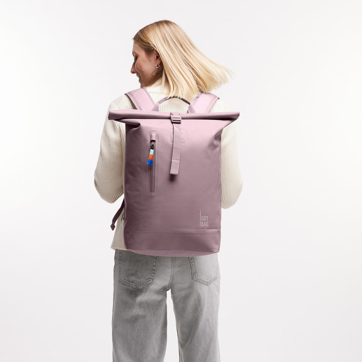 ROLLTOP LITE Rucksack in bass (Salbeigrün) von einer Frau als Rucksack auf dem Rücken getragen.