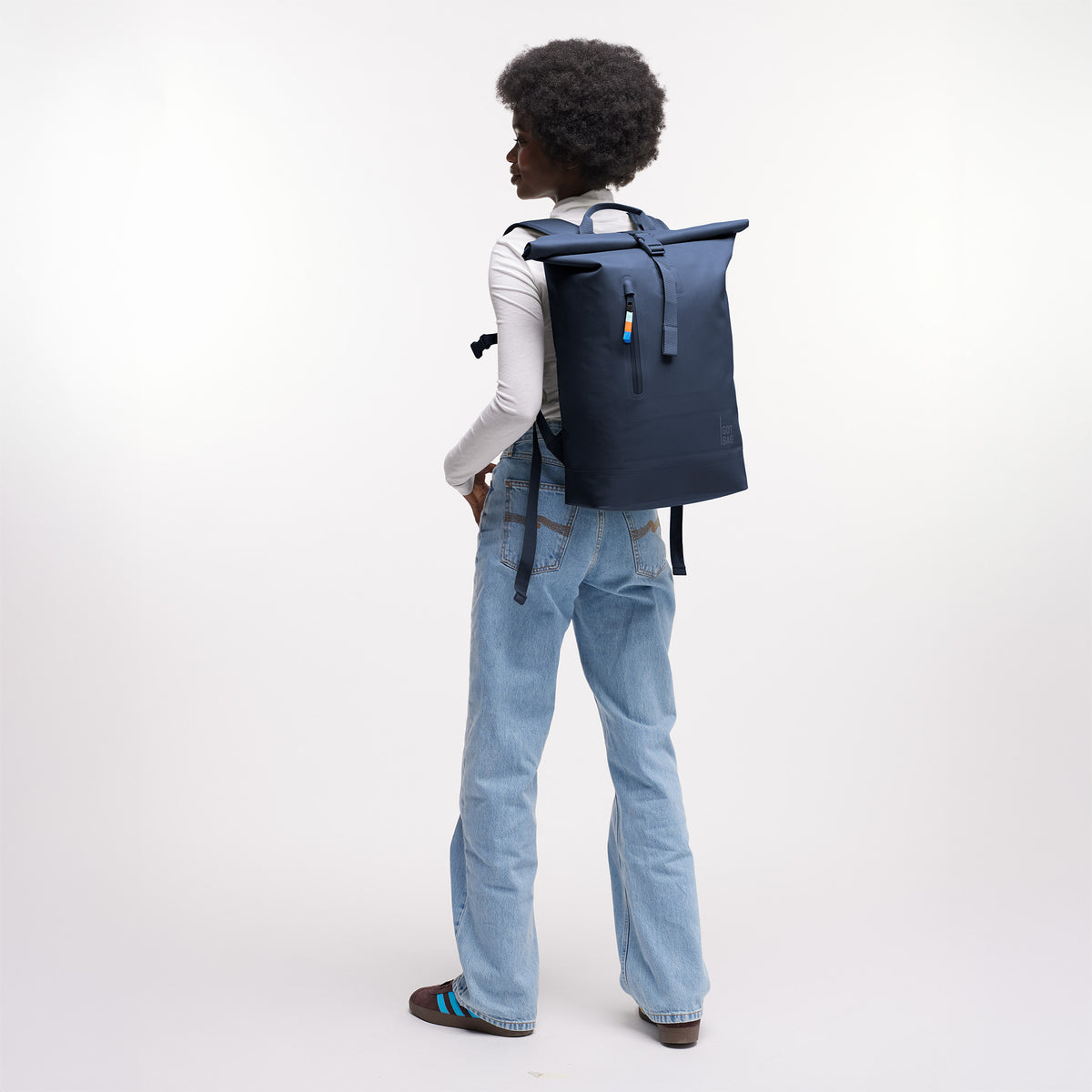 ROLLTOP LITE 2.0 Rucksack in deep ocean (dunkles Marineblau) von einer Frau als Rucksack auf dem Rücken getragen.