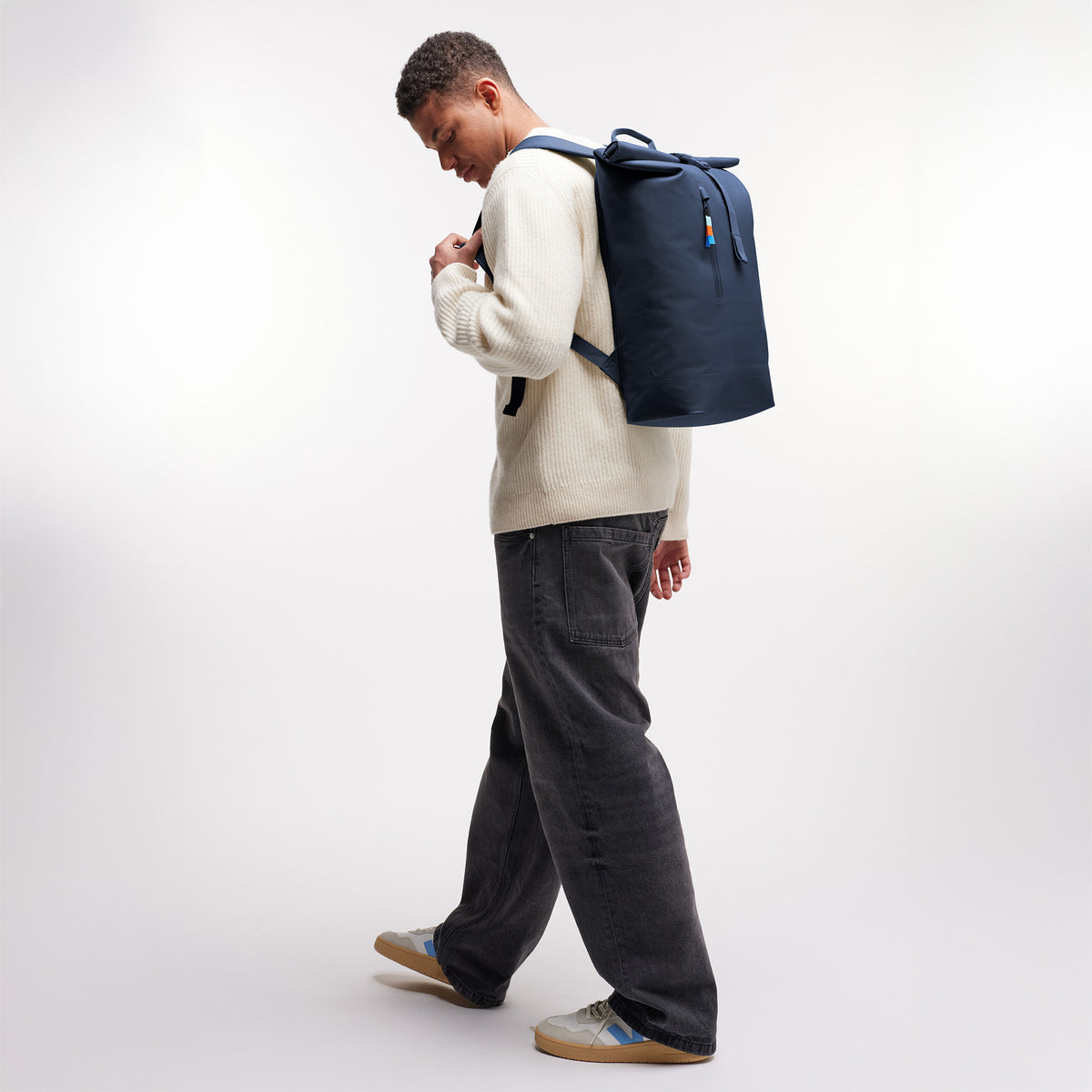ROLLTOP LITE Rucksack in deep ocean (dunkles Marineblau) von einem Mann als Rucksack auf dem Rücken getragen.