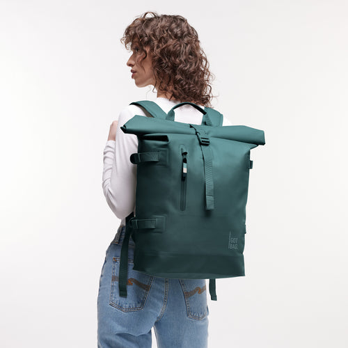 ROLLTOP 2.0 MONOCHROME EDITION Rucksack in sea teal (kühles Türkisgrün) von einer Frau auf dem Rücken getragen.