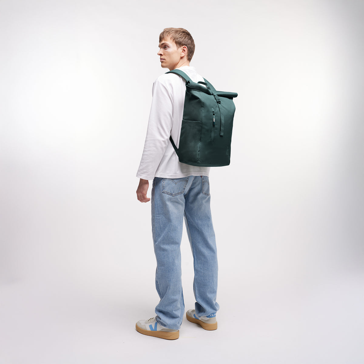 ROLLTOP EASY Rucksack in sea teal (kühles Türkisgrün) von einem Mann auf dem Rücken getragen.