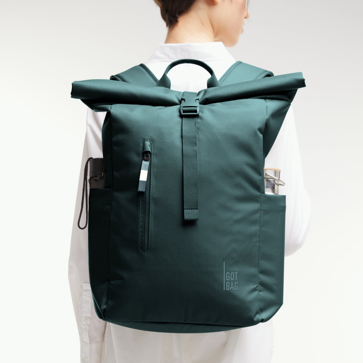 ROLLTOP EASY MONOCHROME EDITION Rucksack in sea teal (kühles Türkisgrün) von einer Frau auf dem Rücken getragen.